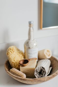 a wooden bowl filled with different types of hair care items and a bottle of alcohol