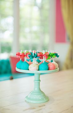 a cake plate topped with blue and pink desserts on top of a wooden table