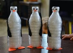 three penguins made out of plastic bottles sitting on a table