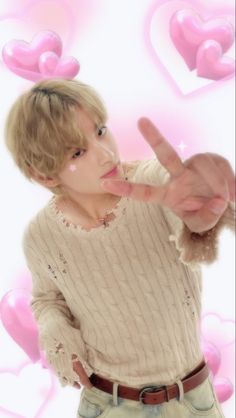 a young man making the peace sign with his hands while standing in front of hearts