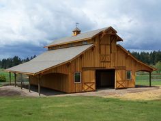 a large wooden barn sitting on top of a lush green field