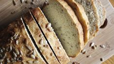 sliced loaf of bread sitting on top of a wooden cutting board with seeds all over it