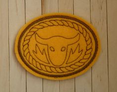 an embroidered patch with a bull's head in the center on a wooden surface