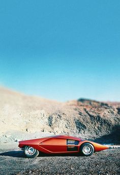 an orange sports car parked in the desert