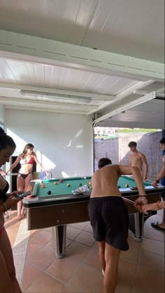 several people are playing pool in an open room