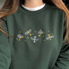 a close up of a person wearing a green sweater with dragon embroidered on the front