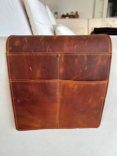 a brown leather bag sitting on top of a white couch