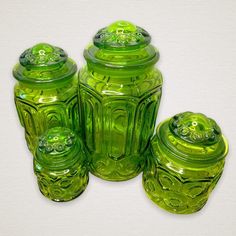 three green glass jars with lids on white background