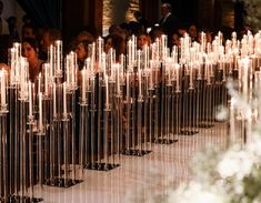 rows of candles are lined up in the middle of a room with people sitting around them