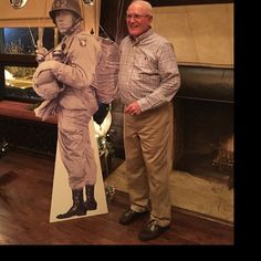 two men standing next to each other in front of a fire place with a statue