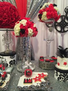 a table topped with red and white flowers in vases next to cake on plates