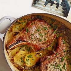 a pot filled with meat and potatoes on top of a table next to a magazine