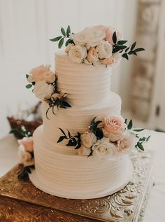 a three tiered white wedding cake with fresh flowers on the top and bottom layer