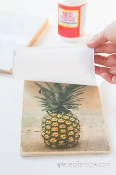 a pineapple on a piece of paper being held by a hand