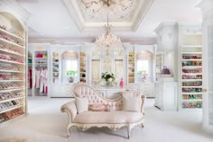 a white closet with chandelier, couch and shoes on the shelves in it