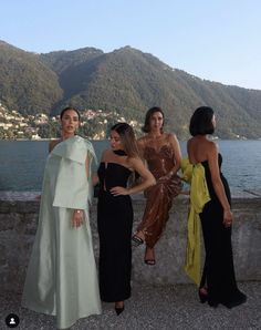 four women standing next to each other near the water