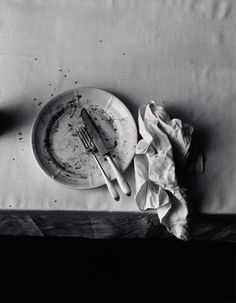 a dirty plate with a knife and fork on it next to a napkin that has been left over