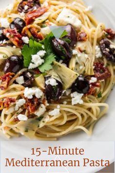 a white plate topped with pasta and olives