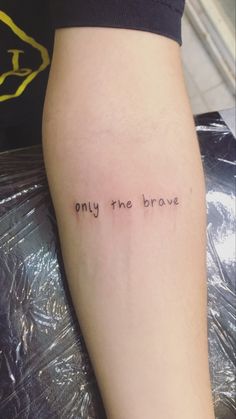 a woman's leg with the words, only the brave written in cursive font