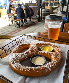 a large pretzel sitting on top of a table next to a cup of beer