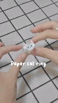 two hands are holding a paper cat ring