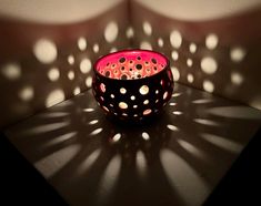 a lit candle sitting on top of a table next to a shadow cast by a wall