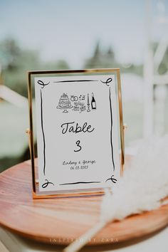 a table with a sign that says table 3 on it and a white feather sitting next to it