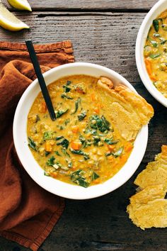 two bowls filled with soup and tortilla chips on top of a wooden table