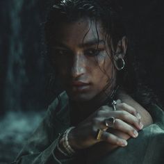 a woman with dark hair and piercings holding her hand on her shoulder in the rain