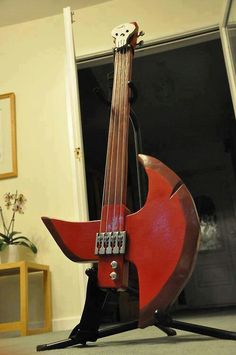 a red guitar sitting on top of a wooden stand