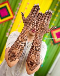 a woman holding her hands up with henna on it