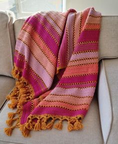 a pink and orange blanket sitting on top of a couch