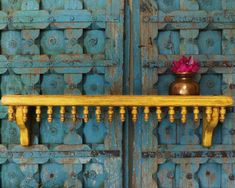 a wooden shelf sitting on top of a blue wall next to a potted plant