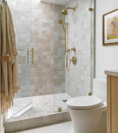 a white toilet sitting next to a walk in shower under a skylight on top of a tiled floor