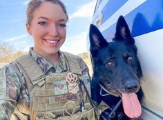 a woman in uniform standing next to a black and brown dog with its tongue hanging out