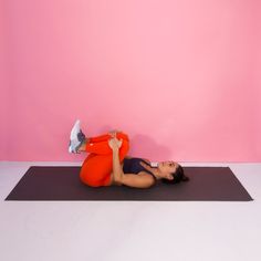 a woman in an orange top is doing yoga