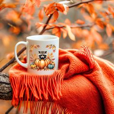 a mug with a raccoon on it sitting on a blanket