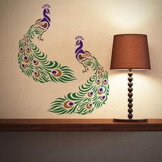 a lamp sitting on top of a table next to a wall with a peacock painted on it