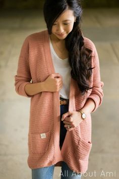 a woman wearing a pink cardigan and jeans