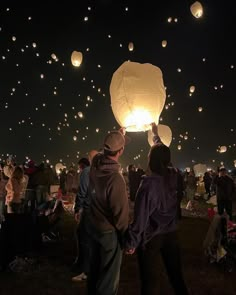 many people are flying lanterns in the sky at night with lights on them, and there is no image here to provide a caption