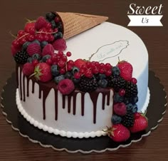 a cake decorated with berries, raspberries and ice cream on a wooden table