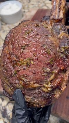 a person wearing black gloves holding up a large piece of meat that has been cooked