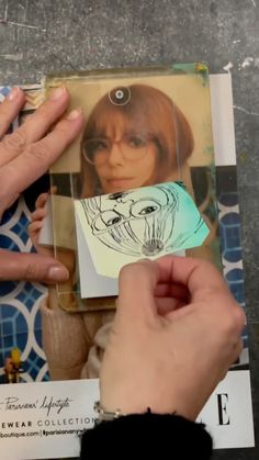 a person holding up a piece of paper with a drawing of a woman's face on it