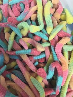 there are many different colored candy worms in the bowl, and they look like wormies