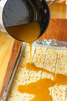 someone is pouring caramel sauce on crackers