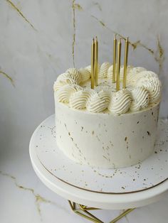 a cake with white frosting and gold sprinkles sitting on a plate