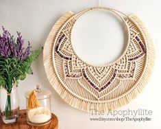 a table topped with vases filled with flowers next to a wicker wall hanging