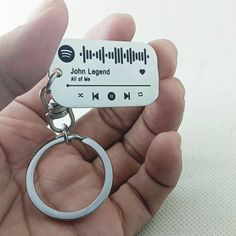 a hand holding a metal keychain with an mp3 player on it