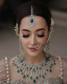 a woman wearing an elaborate necklace and earrings with pearls on her head, in the middle of