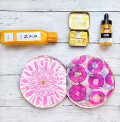 an assortment of cosmetics and other items laid out on a white wooden table with yellow bottles